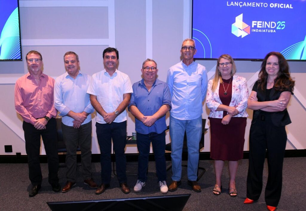 Na foto da esquerda para a direita estão: o vice-diretor, Daniel Jurado; osecretário de Tecnologia, Inovação e Desenvolvimento, José Augusto Rodrigues Gonçalves; o Prefeito de Indaiatuba, Dr. Custódio Tavares (MDB); o vereador, Luiz Alberto Cebolinha Pereira; o diretor titular do Ciesp Indaiatuba, Sergio Roberto Wolf; a vereadora, Clélia Santos e a gerente do Ciesp, Anita Parizzi. As autoridades estão em cima do palco e ao fundo a logomarca da Feind 2025 no telão. Fim da descrição.